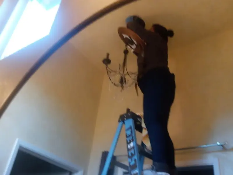 Electrician installing a chandelier in a Hanceville residence